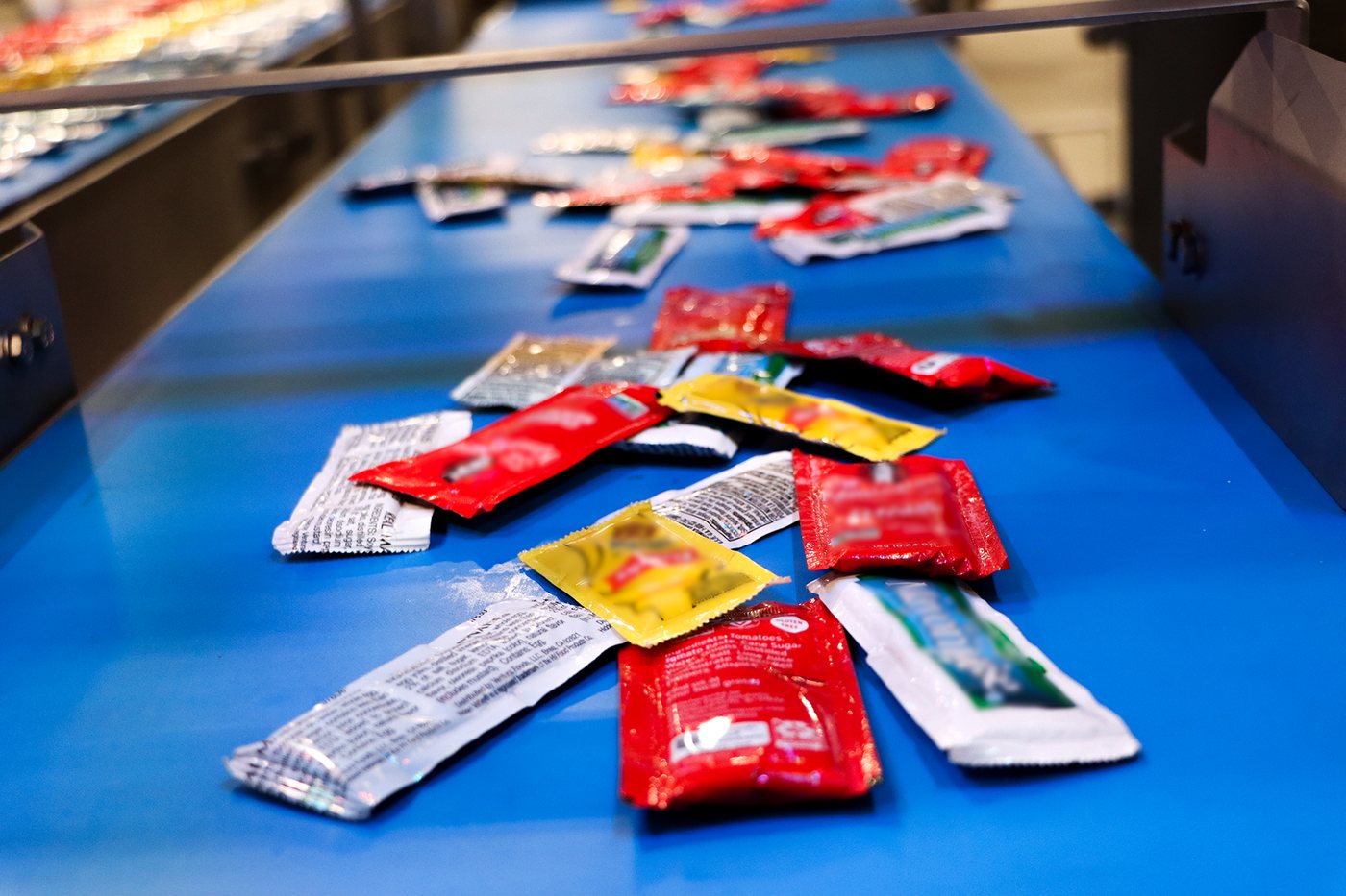 Before: condiment packets arriving in a chaotic, overlapping pile on the JLS Vision AI demo cell infeed