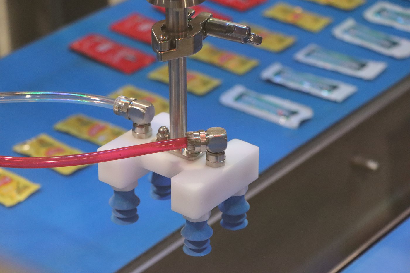 Vacuum end-of-arm tooling on the JLS Vision AI demo cell picking a condiment packet from the sorted flow